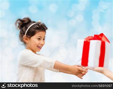 holidays, presents, christmas, childhood and people concept - smiling little girl with gift box over blue lights background