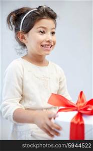 holidays, presents, christmas, childhood and people concept - smiling little girl with gift box at home