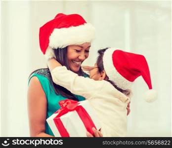 holidays, presents, christmas, x-mas concept - happy mother and child girl in santa helper hats with gift box