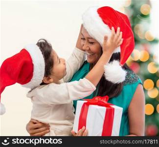 holidays, presents, christmas, xmas concept - happy mother and child girl in santa helper hats with gift box
