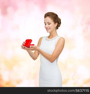 holidays, presents, wedding and happiness concept - smiling woman in white dress holding red gift box over pink lights background