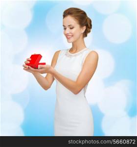 holidays, presents, wedding and happiness concept - smiling woman in white dress holding red gift box over blue lights background