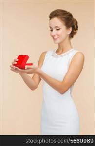 holidays, presents, wedding and happiness concept - smiling woman in white dress holding red gift box over beige background