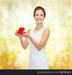 holidays, presents, wedding and happiness concept - smiling woman in white dress holding red gift box over golden lights background