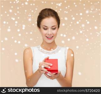 holidays, presents, wedding and happiness concept - smiling woman in white dress holding red gift box over beige background over beige background and snow