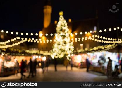 holidays, sale and retail concept - evening christmas market at old town hall square in tallinn bokeh. christmas market at tallinn old town hall square