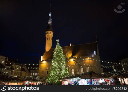 holidays, sale and retail concept - evening christmas market at old town hall square in tallinn. christmas market at tallinn old town hall square