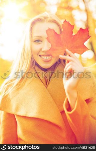holidays, seasons, travel, tourism, happy people concept - smiling woman with red marple leaf in the autumn park