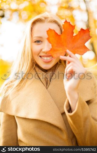 holidays, seasons, travel, tourism, happy people concept - smiling woman with red marple leaf in the autumn park