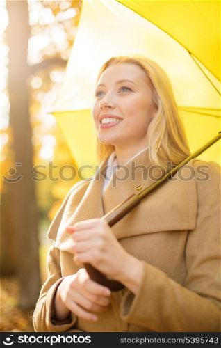 holidays, seasons, travel, tourism, happy people concept - smiling woman with yellow umbrella in the autumn park