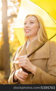 holidays, seasons, travel, tourism, happy people concept - smiling woman with yellow umbrella in the autumn park