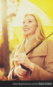 holidays, seasons, travel, tourism, happy people concept - smiling woman with yellow umbrella in the autumn park