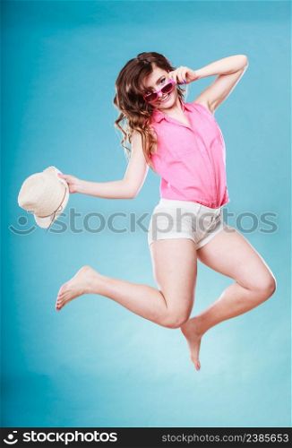 Holidays summer and happiness. Girl in full length casual style straw hat having fun jumping on blue