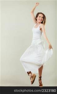 Holidays summer and happiness. Woman wearing white dress jumping. Female model in full length on gray background.