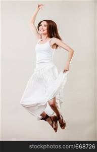 Holidays summer and happiness. Woman wearing white dress jumping. Female model in full length on gray background.
