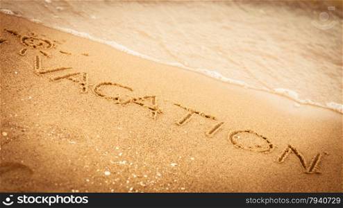 Holidays summer concept. The word vacation written in the sand on beach.