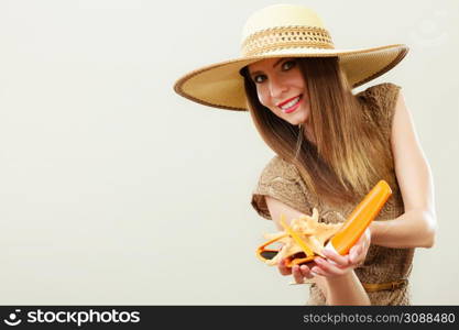 Holidays summer fashion and skin care concept. Woman in straw hat holds sunglasses shell and sunscreen lotion, gray background copy space