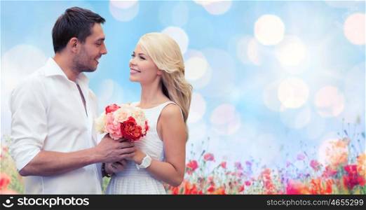 holidays, summer, people and dating concept - happy couple with bunch of flowers over lights and poppy field background