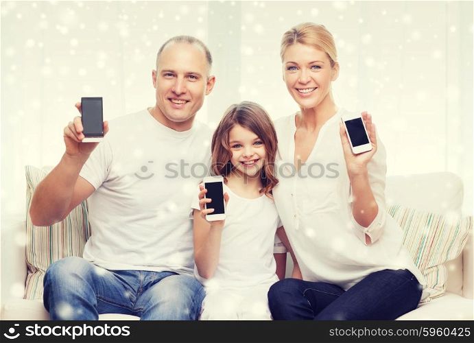holidays, technology, advertisement and people concept - smiling family showing smartphones blank screens over snowflakes background