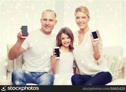 holidays, technology, advertisement and people concept - smiling family showing smartphones blank screens over snowflakes background
