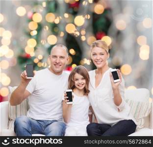 holidays, technology, advertisement and people concept - smiling family with smartphones over living room and christmas tree background