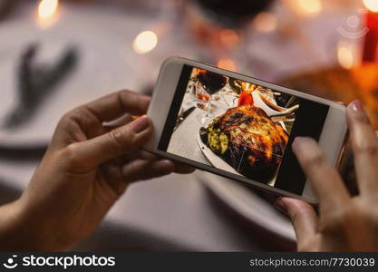 holidays, technology and celebration concept - hands with smartphone photographing food at christmas dinner. hands photographing food at christmas dinner
