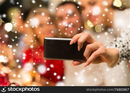 holidays, technology and people concept - close up of friends taking selfie by smartphone on christmas over snow. close up of friends taking selfie on christmas