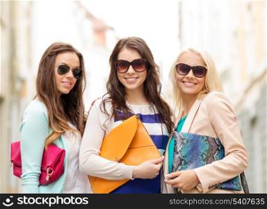holidays, tourism and happy people concept - three smiling women in sunglasses with bags in the city