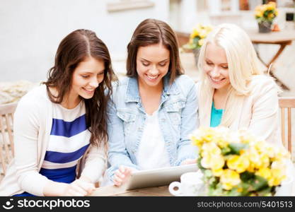 holidays, tourism and internet - beautiful girls looking at tablet pc in cafe outside