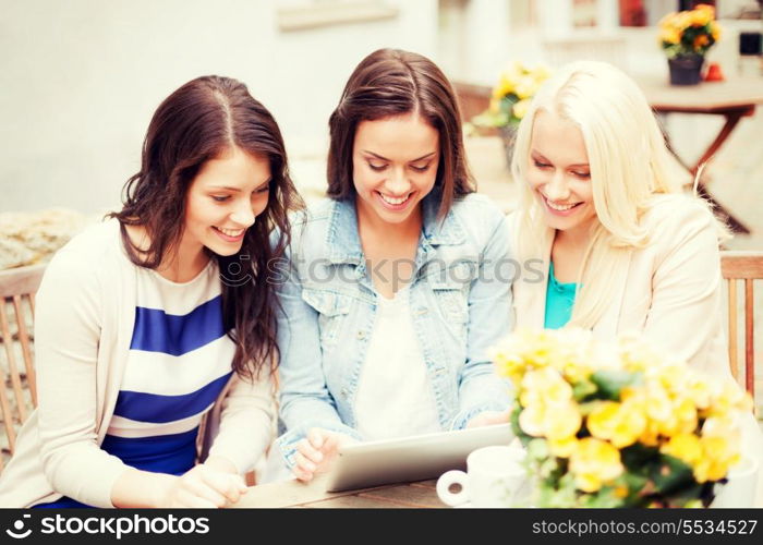 holidays, tourism and internet - beautiful girls looking at tablet pc in cafe outside