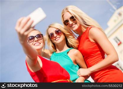 holidays, tourism and modern technology concept - smiling girls taking picture with smartphone camera in the city