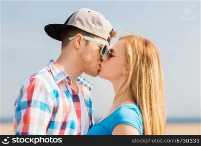 holidays, vacation and love concept - teenage couple kissing outdoors