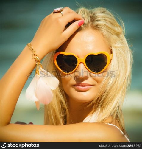 Holidays, vacation and summer fashion concept. Closeup attractive blonde girl in orange heart shaped sunglasses outdoor on beach water background