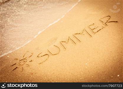 Holidays vacation concept. The word summer written in the sand on beach.