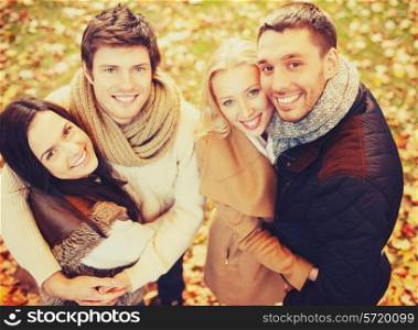 holidays, vacation, happy people concept - group of friends or couples having fun in autumn park