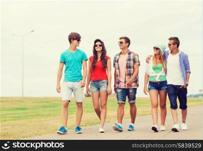 holidays, vacation, love and friendship concept - group of smiling teenagers walking outdoors
