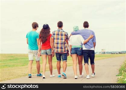 holidays, vacation, love and friendship concept - group of teenagers walking outdoors from back