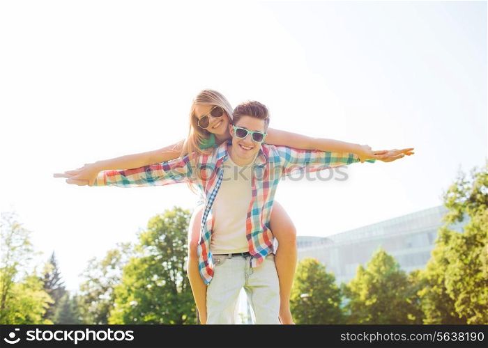 holidays, vacation, love and friendship concept - smiling couple having fun in park