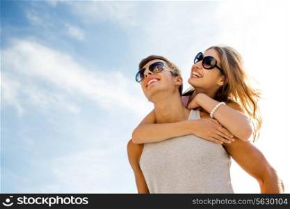 holidays, vacation, love and friendship concept - smiling couple having fun over sky background
