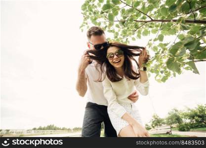 holidays, vacation, love and friendship concept - smiling couple in sunglasses having fun in summer park.. holidays, vacation, love and friendship concept - smiling couple in sunglasses having fun in summer park