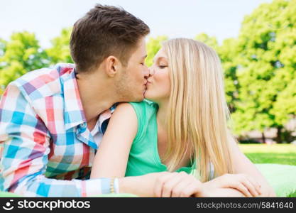 holidays, vacation, love and friendship concept - smiling couple kissing in park