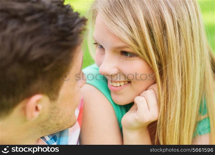 holidays, vacation, love and friendship concept - smiling couple looking at each other in park