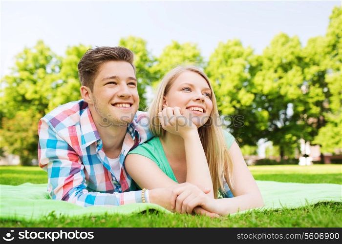 holidays, vacation, love and friendship concept - smiling couple lying on blanket in park