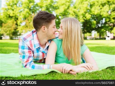 holidays, vacation, love and friendship concept - smiling couple lying on blanket in park