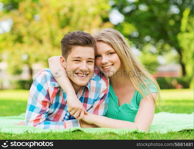 holidays, vacation, love and friendship concept - smiling couple lying on blanket in park