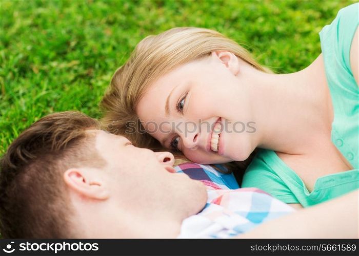 holidays, vacation, love and friendship concept - smiling couple lying on on grass in park