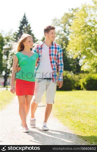 holidays, vacation, love and friendship concept - smiling couple walking in park