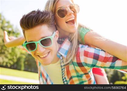 holidays, vacation, love and friendship concept - smiling teen couple in sunglasses having fun in summer park
