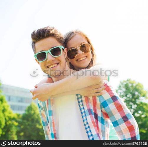 holidays, vacation, love and friendship concept - smiling teen couple in sunglasses having fun in summer park