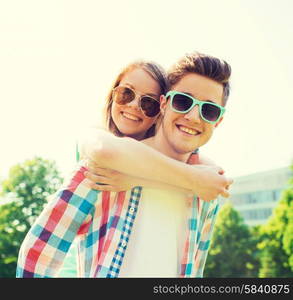 holidays, vacation, love and friendship concept - smiling teen couple in sunglasses having fun in summer park